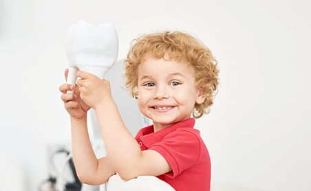 boy holding plastic tooth