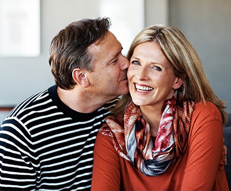 man kissing woman's cheek