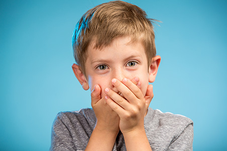 young boy covering his mouth