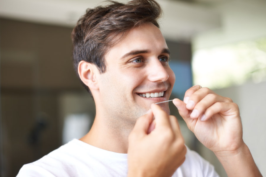 Brown haired man flossing his teeth.