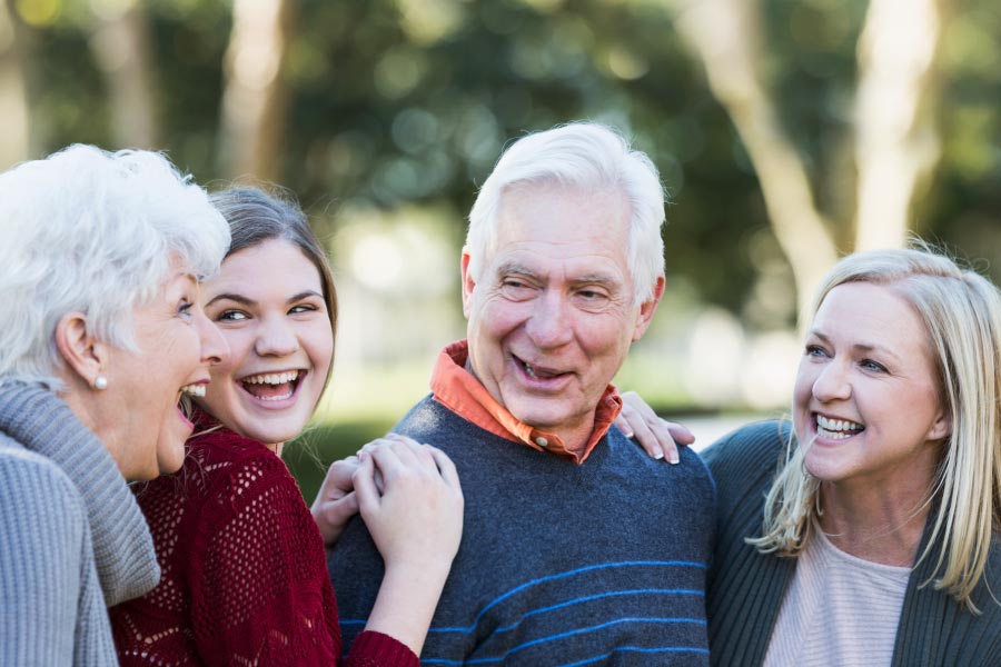 Senior couple smiling and talking with younger family members.