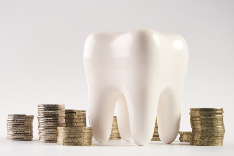 Photo of an oversized tooth next to a stack of coins.