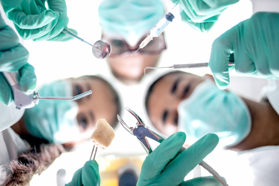 Masked dental professionals preparing for a dental extraction.